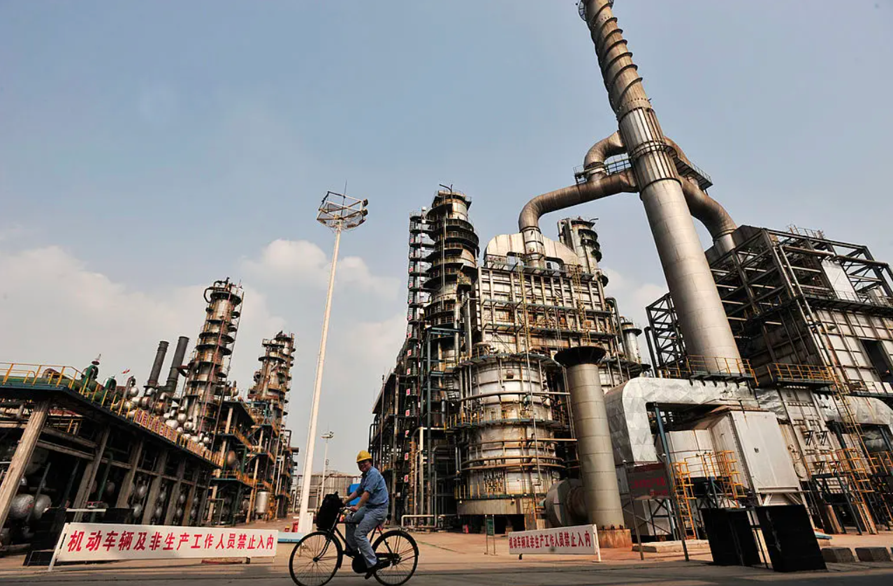 Een werknemer fietst bij een olieraffinaderij van China’s Sinopec in Wuhan, een stad in de Chinese provincie Hubei, op 10 mei 2011. Foto: STR/AFP/Getty Images